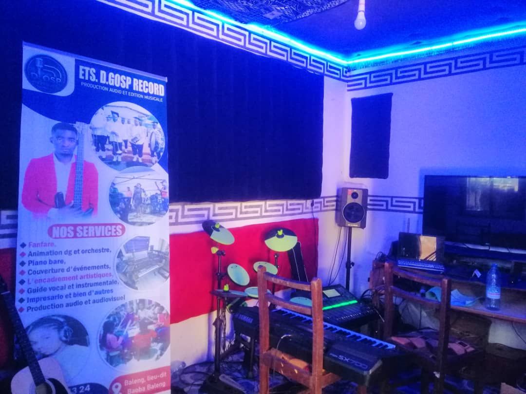 Studio insonorisé éclairé en bleu avec pads de batterie et régie